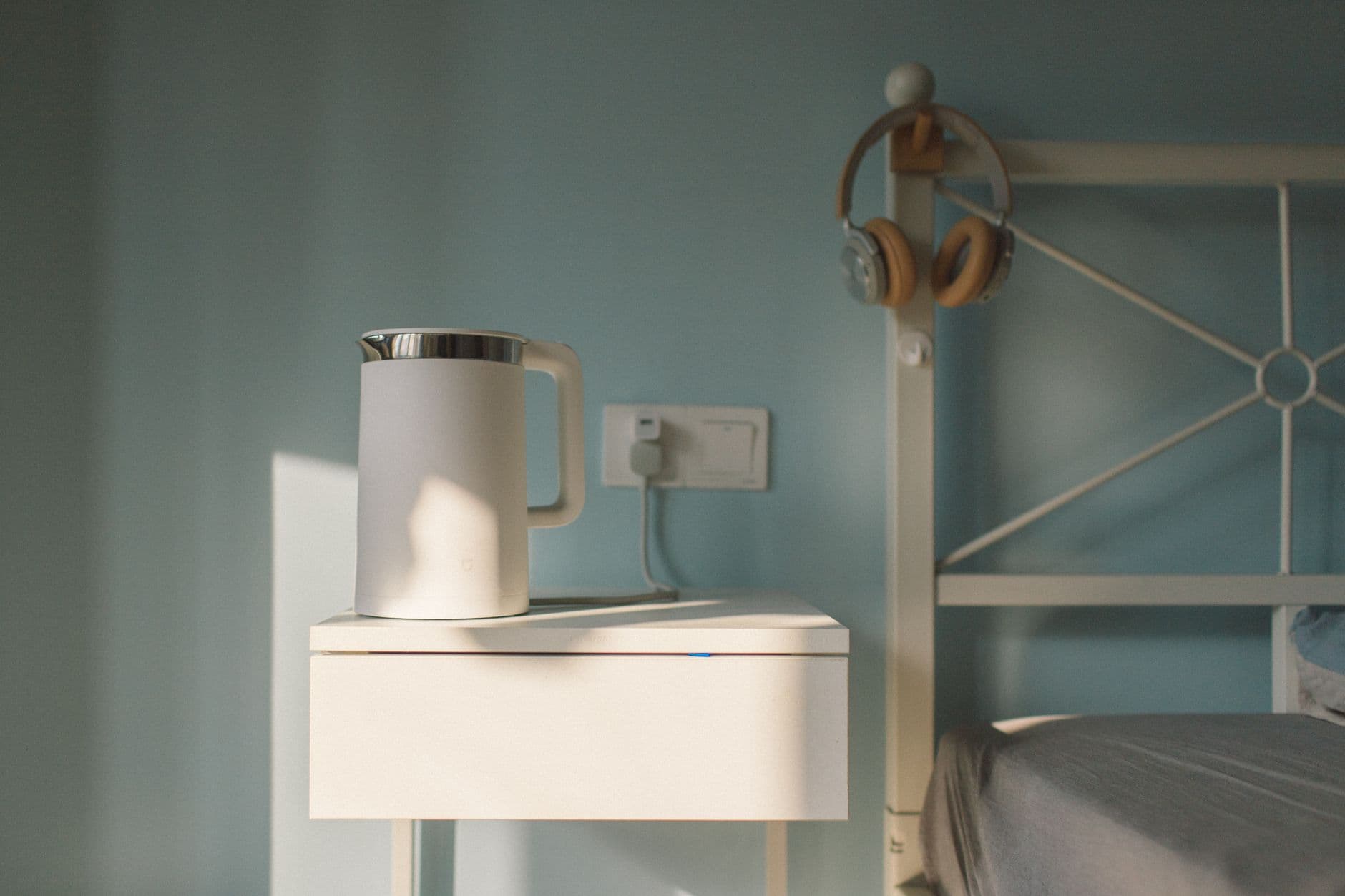 A serene minimalist bedroom scene featuring a white bedside table and a kettle. — dehumidifier review context